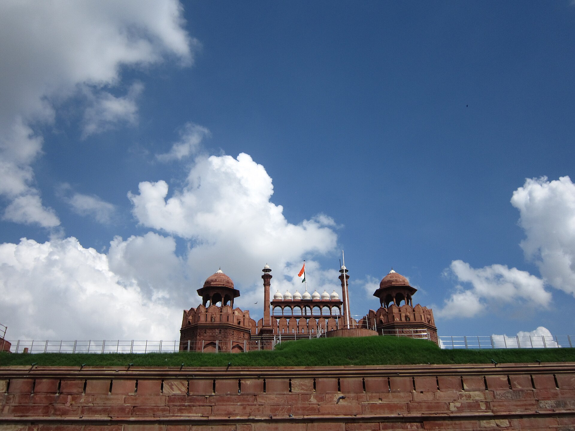 Indian national flag waving against a clear blue sky at Red Fort, Delhi